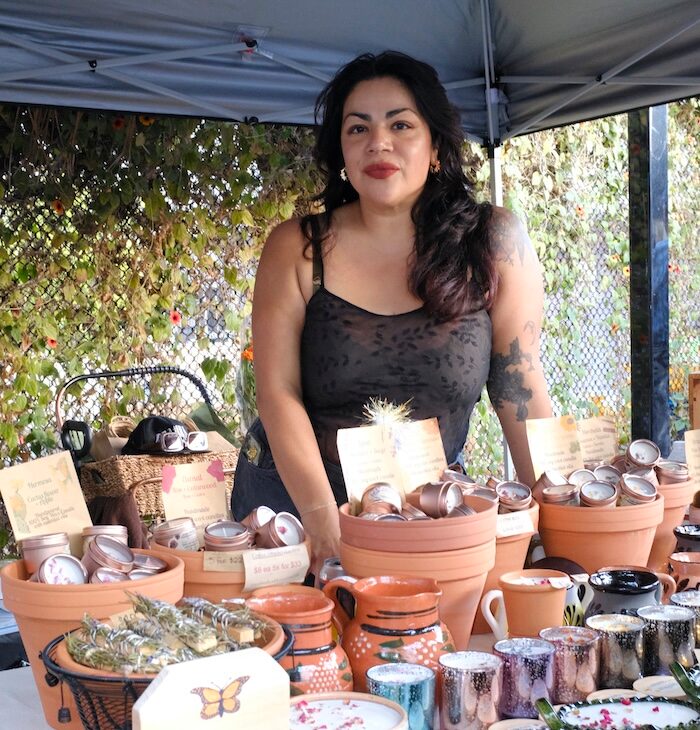 Vendor smiling behind a table of handmade goods