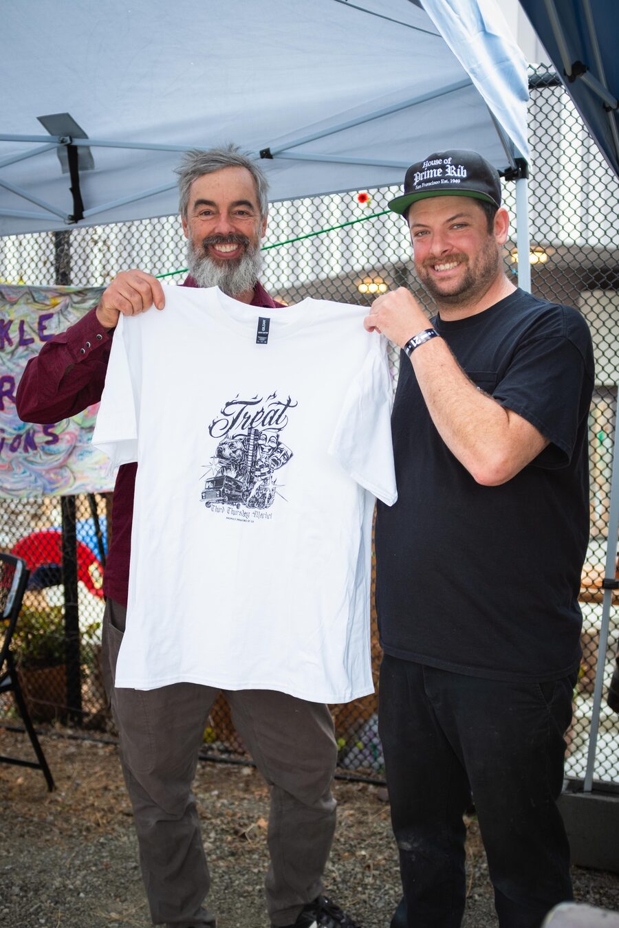 Two vendors holding up a Treat T-shirt